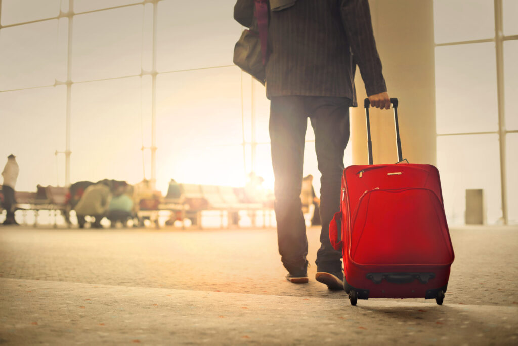 Man walking at an airport carrying a suitcase