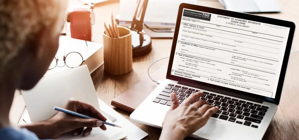 Person typing on the keyboard of a laptop with the Form 700 Statement of Economic Interests Cover Page on the screen.